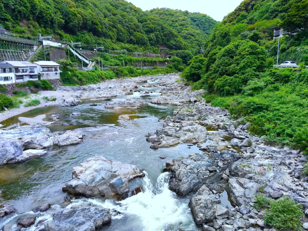 山あいの渓谷を流れる川と、線路沿いの斜面・擁壁